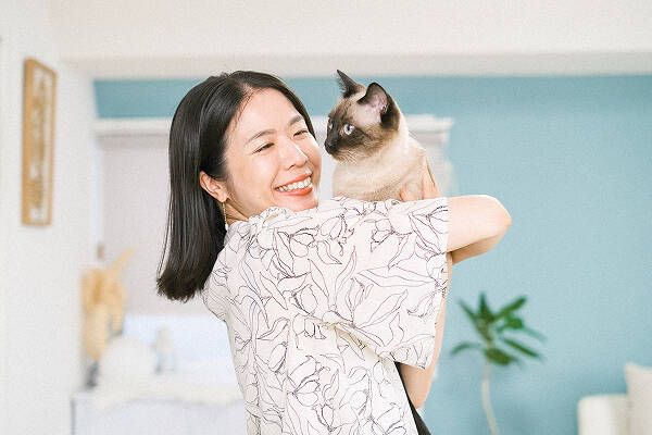 ペットの猫を抱き抱える笑顔の女性の写真